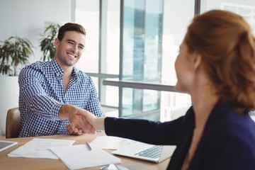 Smiling executives shaking hands at desk