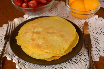 Stack of sweet pancakes decorated on a plate on a wooden table.