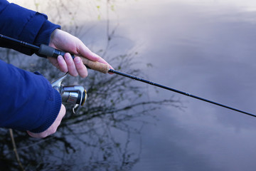 Man catches fish, a close up of a hand and the spinning reel. Fishing with a spinning on the river. 