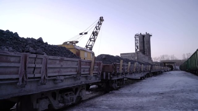 PAN of sets of gandola cars with copper ore in winter. Excavator boom in the background.