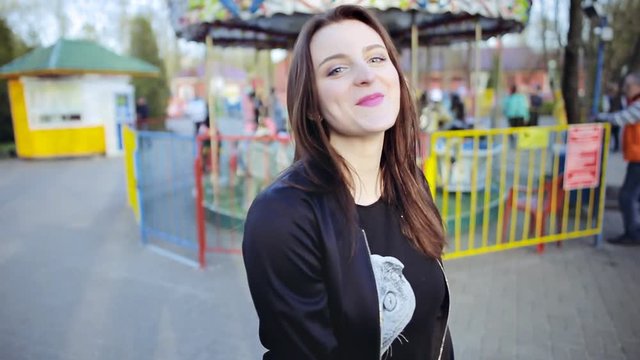 Young attractive brunette woman posing in amusement park at sunset