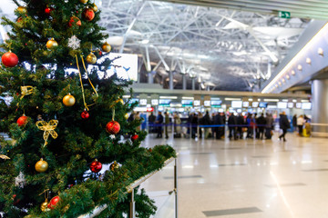 Christmas tree in the airport and people at the check-in counters