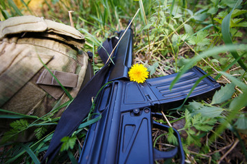 Military helmet, rifle and a flower in the grass close up