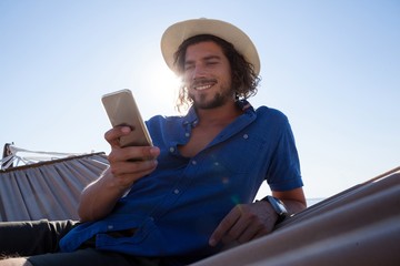 Smiling man using mobile phone while relaxing 