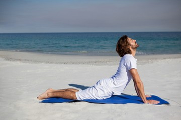 Man performing yoga at beach