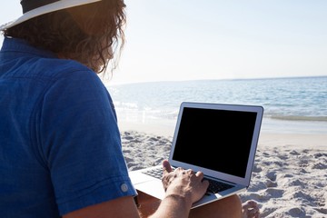 Man using laptop on the beach
