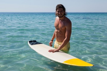 Surfer with surfboard standing in sea