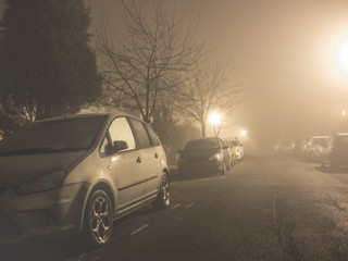 Fototapeta na wymiar Parked cars in night time fog.