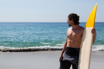 Surfer with surfboard standing at beach coast