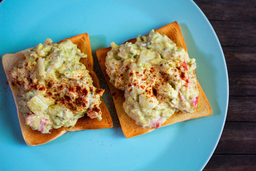 Two sandwiches with avocado salad on blue plate. Crunchy toast with vegetarian salad