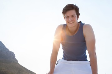 Fototapeta na wymiar Smiling man taking break after jogging on beach