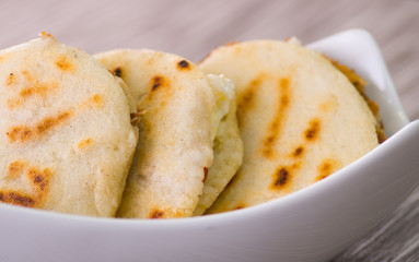Close up of a traditional delicious arepas, shredded chicken avocado and cheddar cheese and shredded beef on wooden background