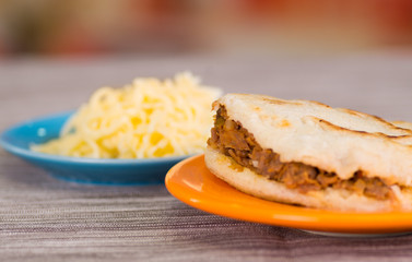 Traditional delicious arepas, shredded chicken avocado and cheddar cheese and shredded beef on wooden blackground