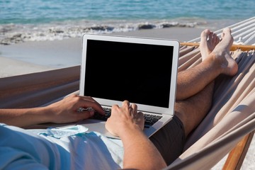 Man using laptop while relaxing on hammock
