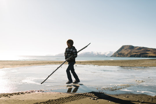 Boy playing with stick on beach