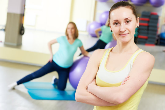 female portrait of coach for pregnant woman doing fitness ball exercise