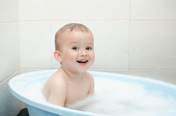 Happy baby boy taking a bath