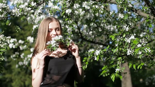 Young beautiful girl with a branch of a blossoming apple tree
