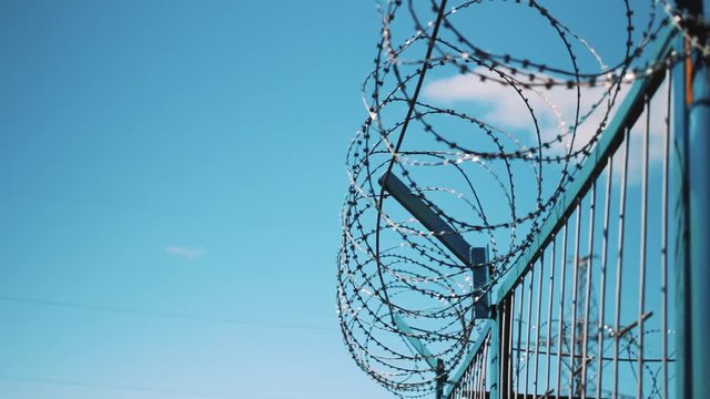 Barbed wire fence against the sky. Prison fencing, cameras, fence of the enterprise. Unauthorized entry is prohibited.