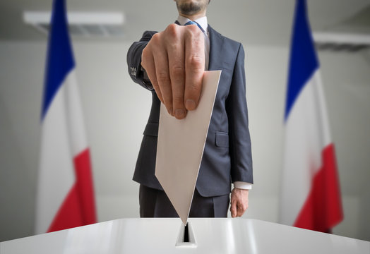 Election in France. Voter holds envelope in hand above vote ball. Wide angle photo.