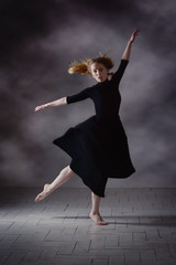 Modern ballet dancer posing on dark background