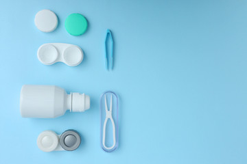 Cases for contact lenses, tweezers and bottle of solution on blue background