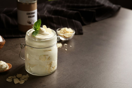 Delicious coconut cream in jar on dark background
