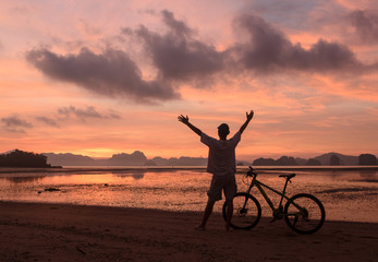 Silhouette of a man and  bicycle on beach