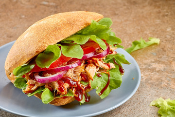 Sandwich with pulled pork, tomato and salad on blue dish