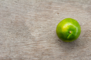 One green color lime on wooden table background
