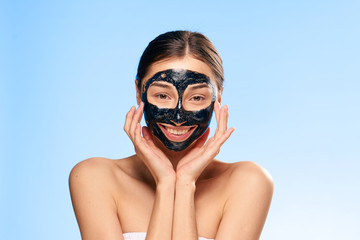 happy young woman with facial mask on blue background