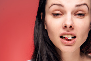 brunette on a red background with a tablet in the tooth...