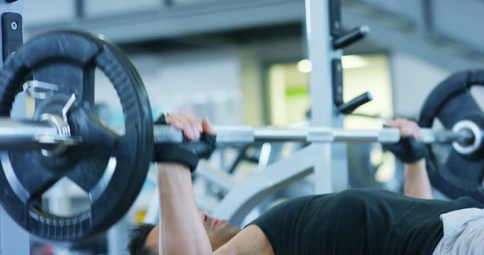 Guy bodybuilder in the gym, works with a barbell, bench press, improving triceps, large pectorals muscle, anterior deltoids muscle Concept love sports, go to the gym, eat right, slim body, be healthy.