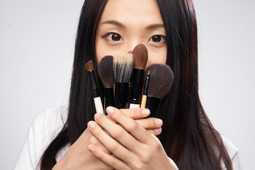 many different brushes for make-up in the hands of women