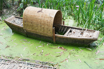 Abandoned chinese bamboo boat in green water - Powered by Adobe