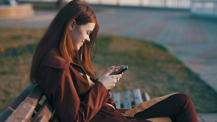 happy woman on the bench, look at the touch phone