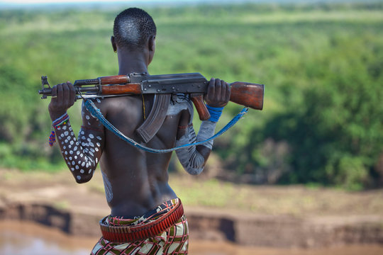 Kara Tribe man with rifle looking across the Omo River, Ethiopia