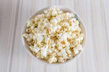 Popcorn in white bowl closeup on wood table