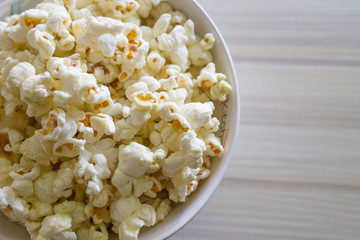 Popcorn in white bowl closeup on wood table