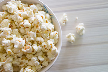 Popcorn in white bowl closeup on wood table