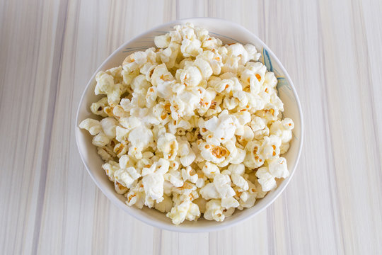 Popcorn in white bowl closeup on wood table