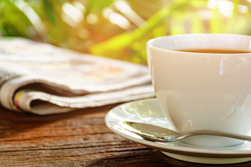 coffee cup clock and news paper on old wooden table