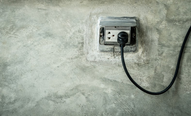 Power cord and electrical plug socket on cement ground.