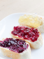 Three pieces of french bread with apple, cherry, blueberry jam