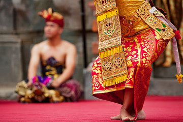 Asian travel background. Beautiful Balinese dancer woman in traditional Sarong costume dancing Legong dance. Legs movements. Arts, culture of Indonesian people, Bali island festivals.