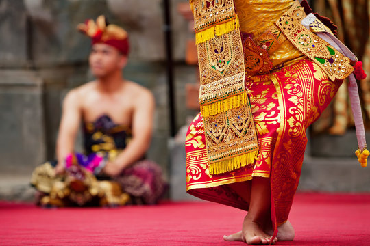 Asian travel background. Beautiful Balinese dancer woman in traditional Sarong costume dancing Legong dance. Legs movements. Arts, culture of Indonesian people, Bali island festivals.