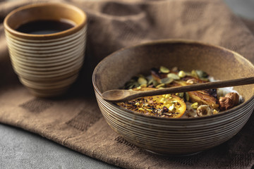 porridge with fried banana and orange. Bowl of oatmeal porridge with banana, Cinnamon. Hot and healthy food for Breakfast, with toast and coffee, on a wood round table with a butter knife.