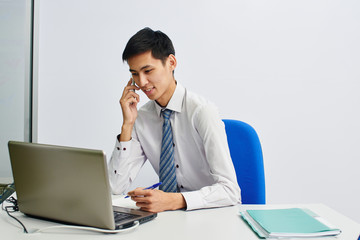 Kazakh young man office worker at the table talking on the phone