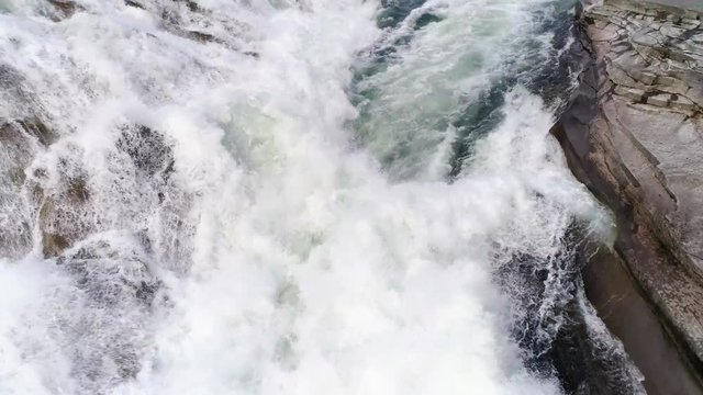 Drone Following Waterfall Flow Close Up Down Rock Cliffs with Misty White Water