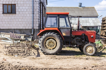 Agricultural machinery and equipment . Tractor with a harrow for cultivating plowed land. The yard of a dairy farm. Podlaskie, Poland.